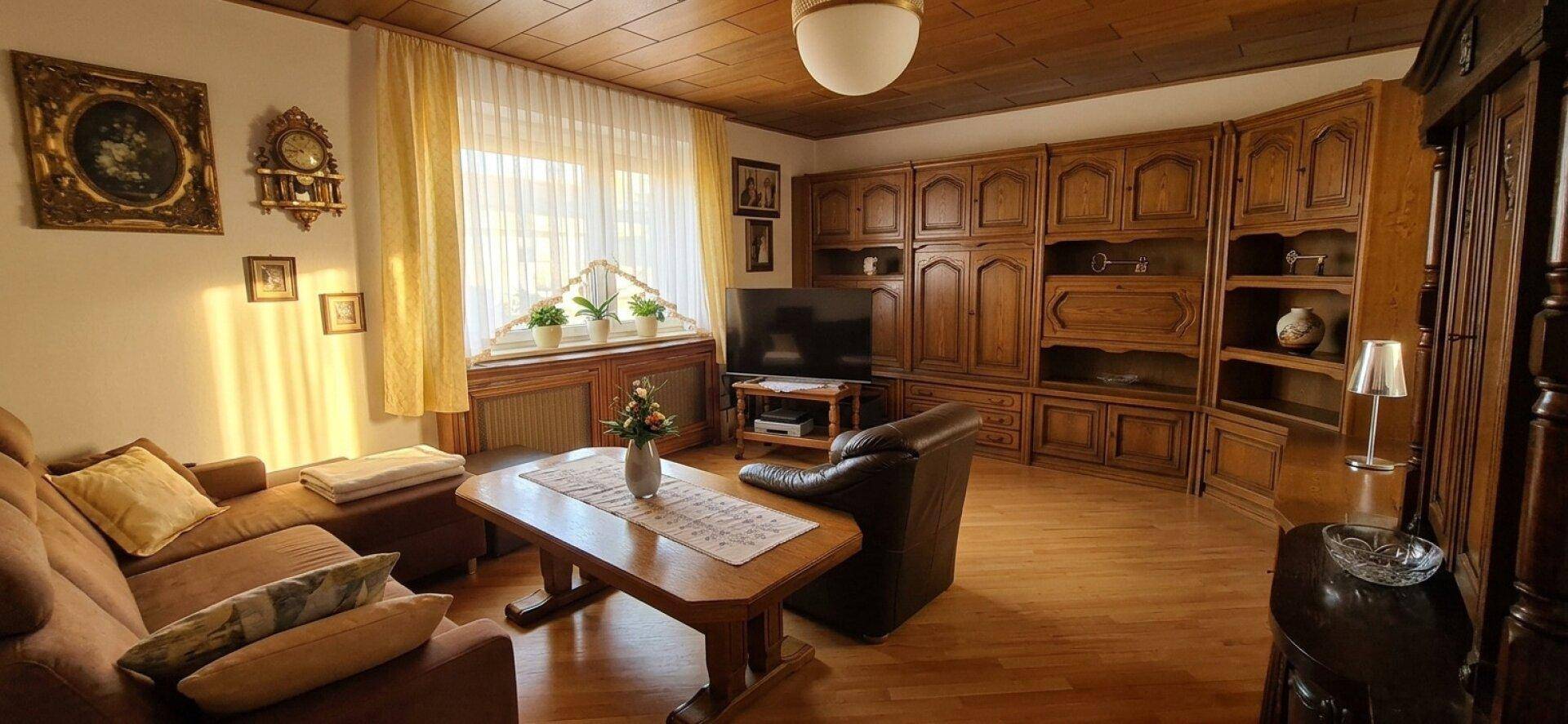 Gemütliches Wohnzimmer mit Holzdecke, Parkettboden und traditionellen Holzmöbeln, gut beleuchtet.