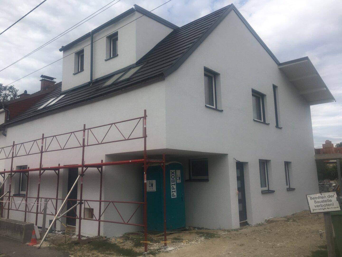 Neubau-Einfamilienhaus mit weißer Fassade und Satteldach, noch im Bau befindlich.