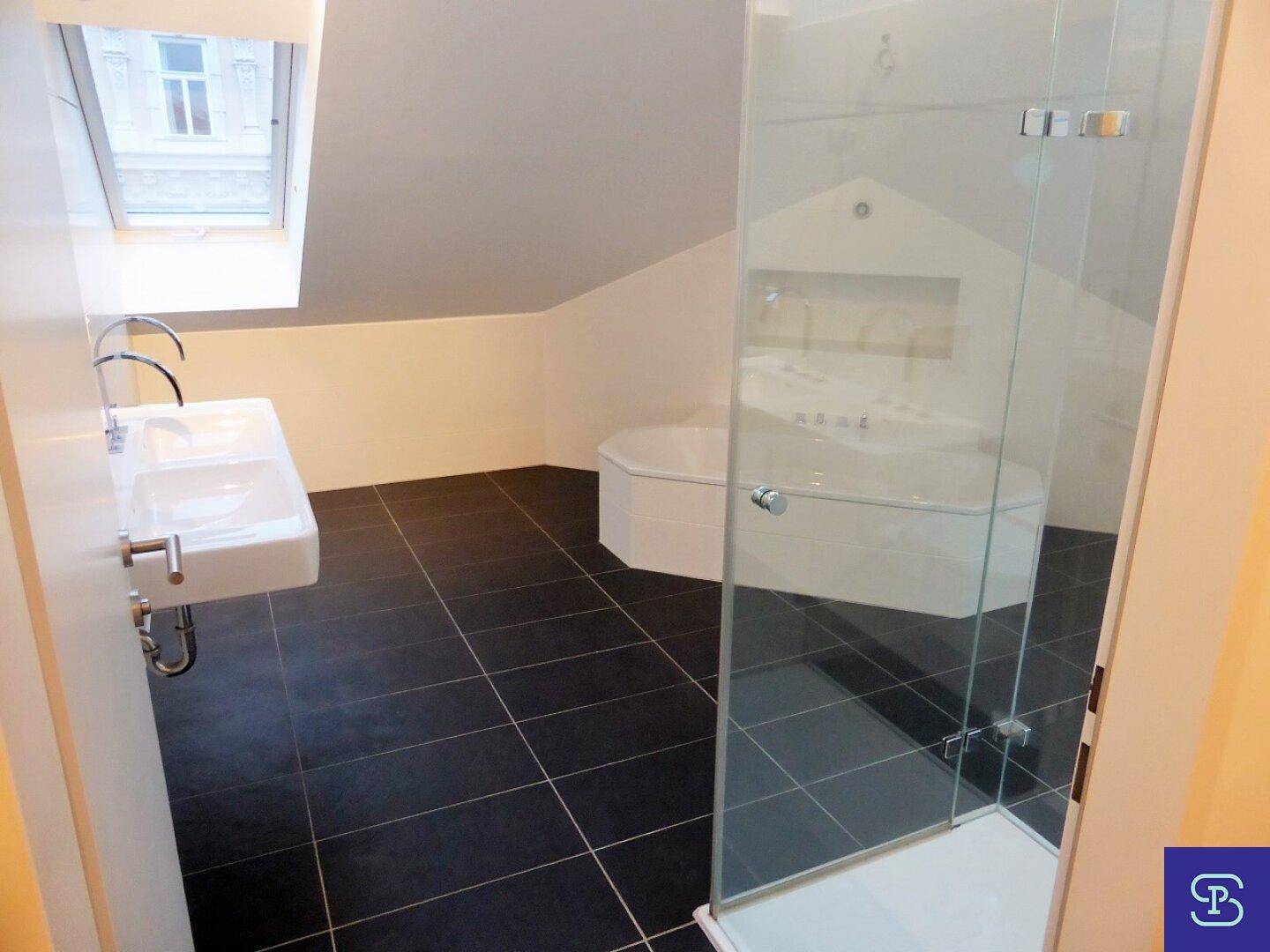 Modernes Badezimmer mit dunklen Fliesen, Dusche und Badewanne unter Dachschräge.