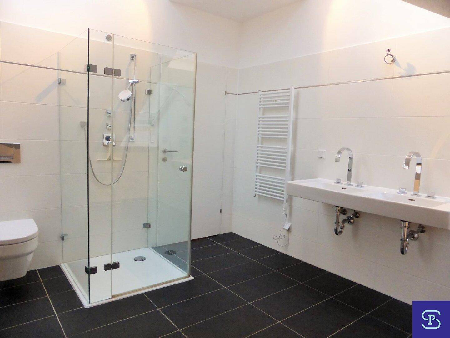 Modernes Badezimmer mit Doppelwaschbecken, Dusche und beheiztem Handtuchhalter.