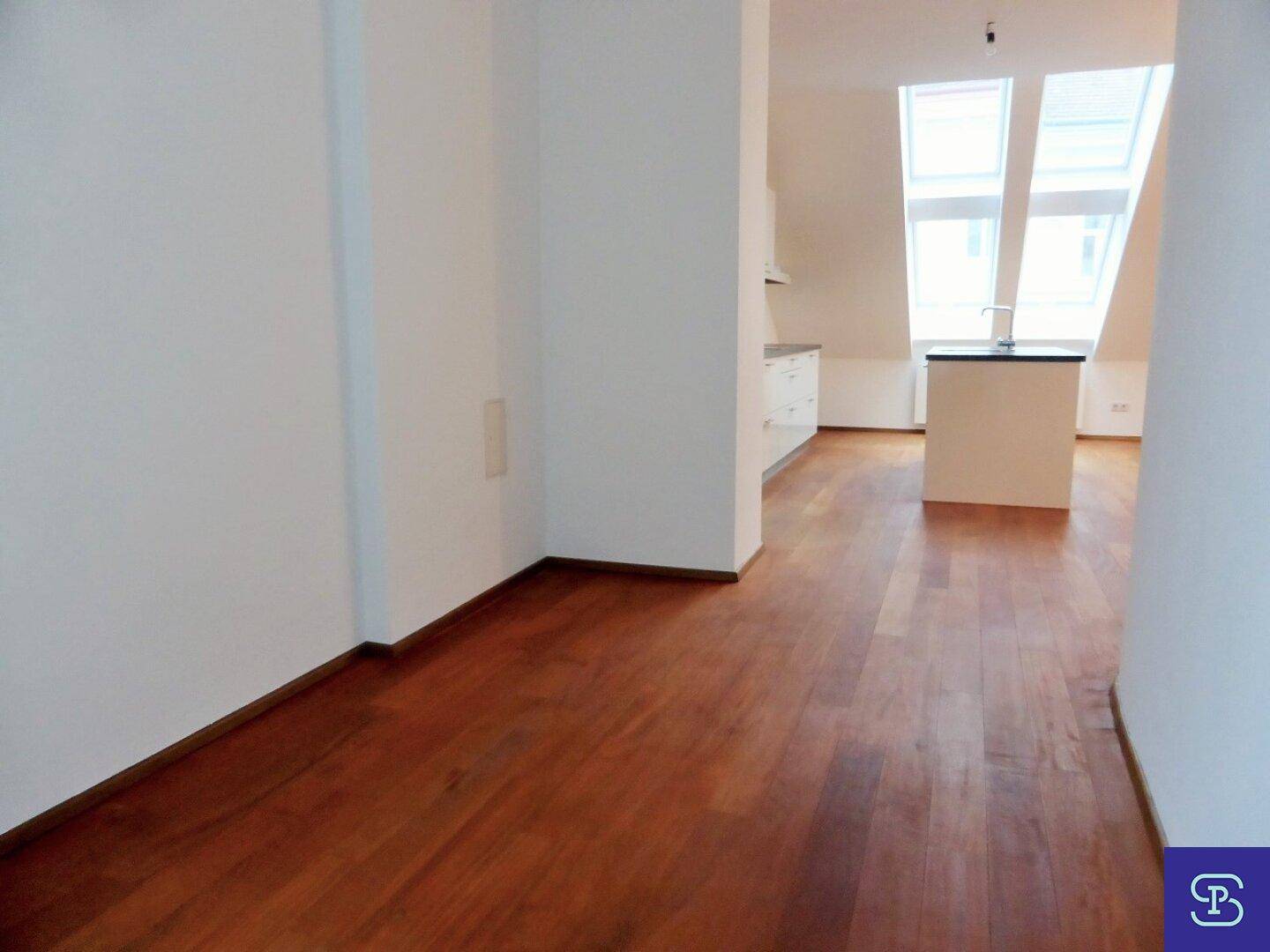 Heller Wohnbereich mit Holzboden und Zugang zur offenen Küche.