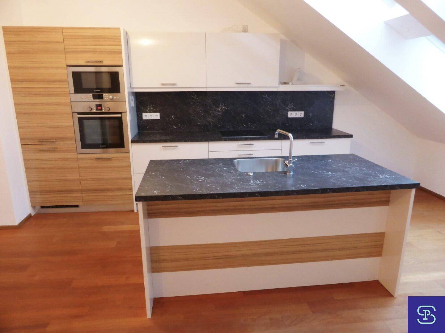 Helle Küche mit weißen Schränken, Holzfronten und dunkler Arbeitsplatte.