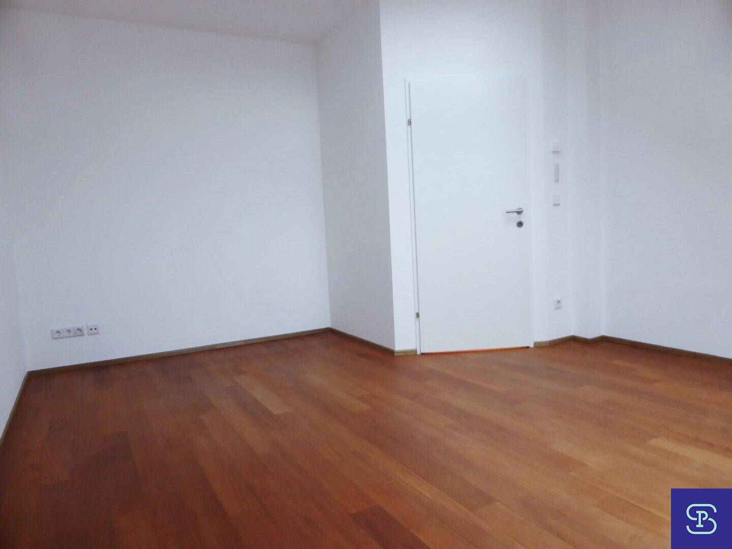 Geräumiges Zimmer mit Holzboden und weiß gestrichenen Wänden.