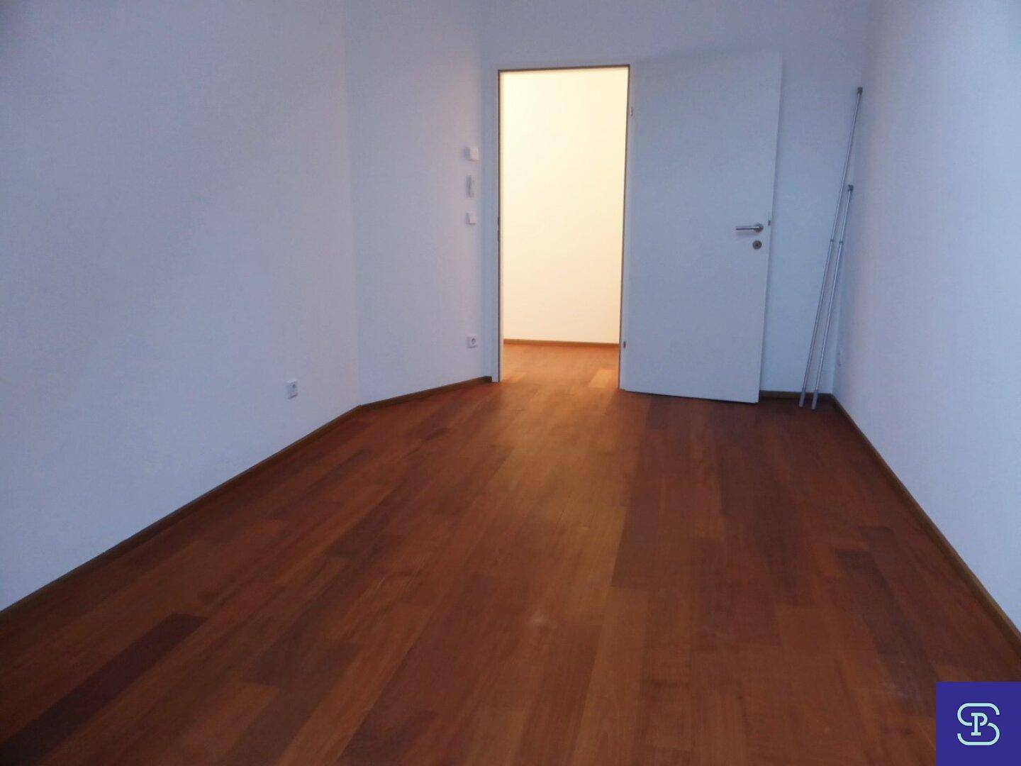 Geräumiges Zimmer mit Holzboden und weiß gestrichenen Wänden.
