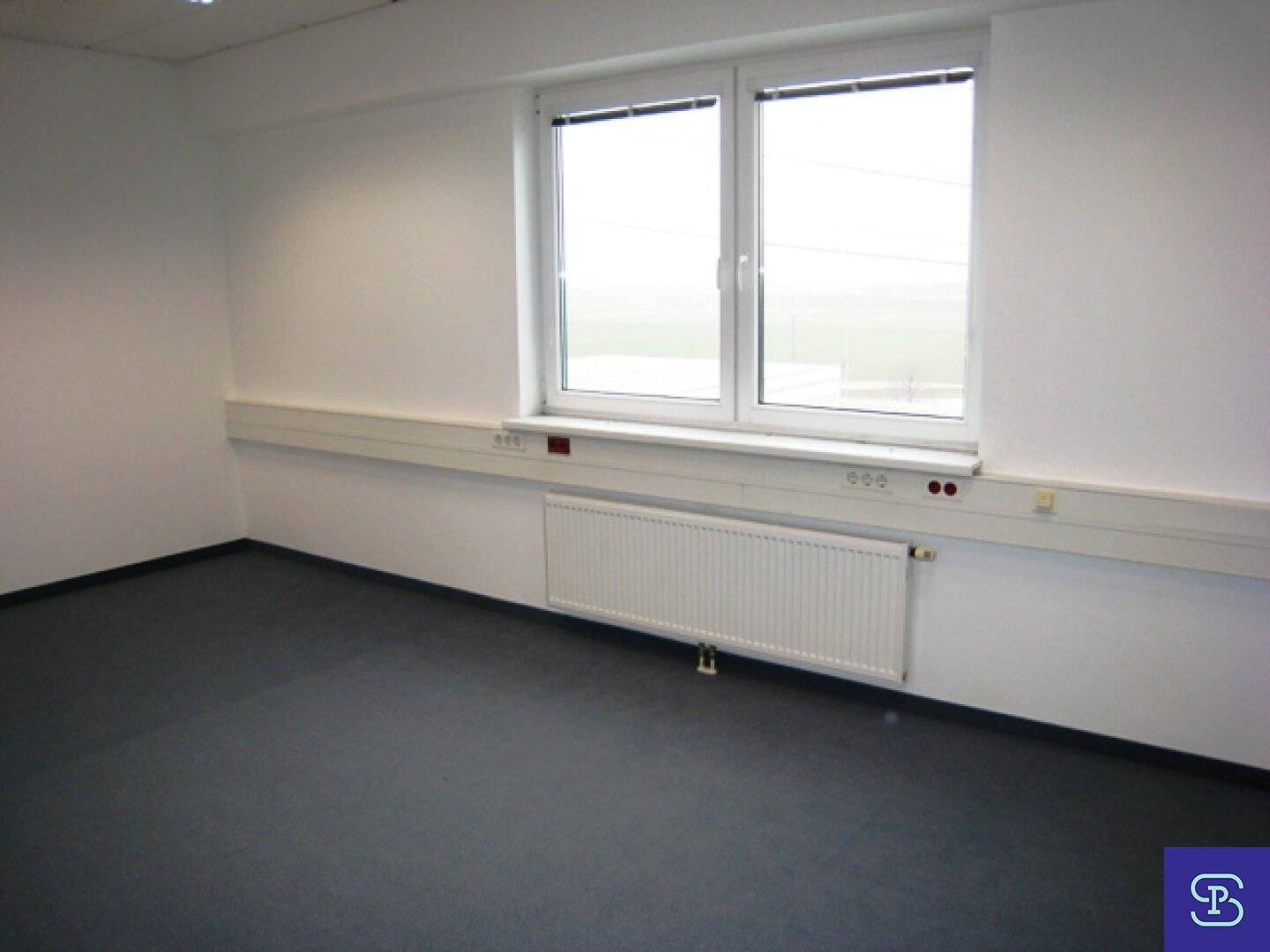 Detailansicht eines Büroraums mit großem Fenster, Heizkörper und Wandkanälen für Verkabelung.