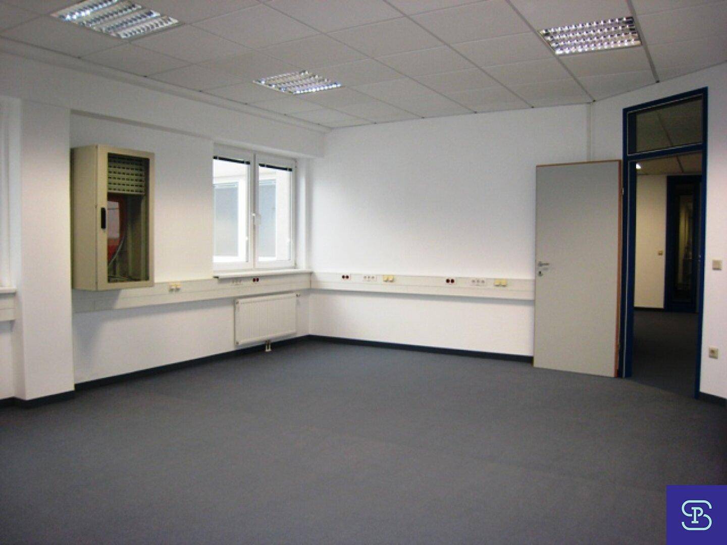 Helles Büro mit Fenstern, Teppichboden und einem Wandschrank, bereit für die Nutzung.