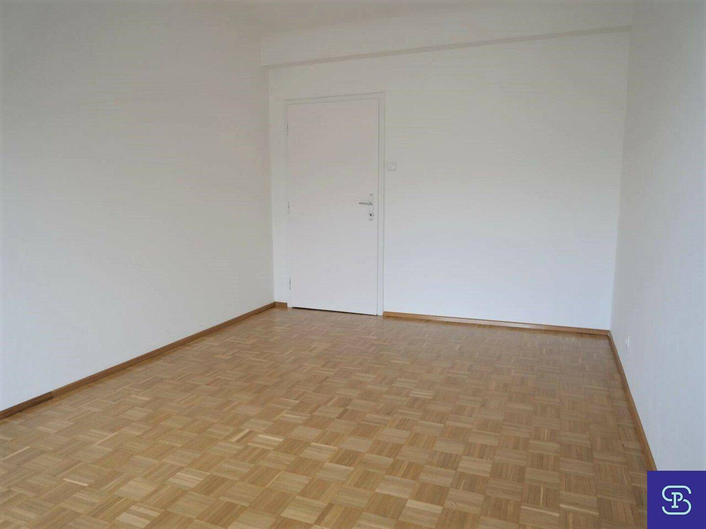 Leeres Zimmer mit Parkettboden und weißer Tür, bereit zur individuellen Gestaltung.