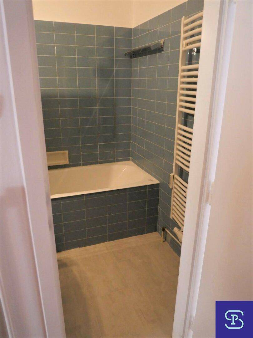 Badezimmer mit blauen Wandfliesen, Badewanne und beheiztem Handtuchhalter.