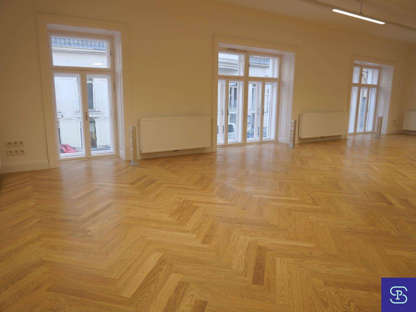 Große Fensterfronten mit Heizkörpern und Blick auf die umliegenden Gebäude.
