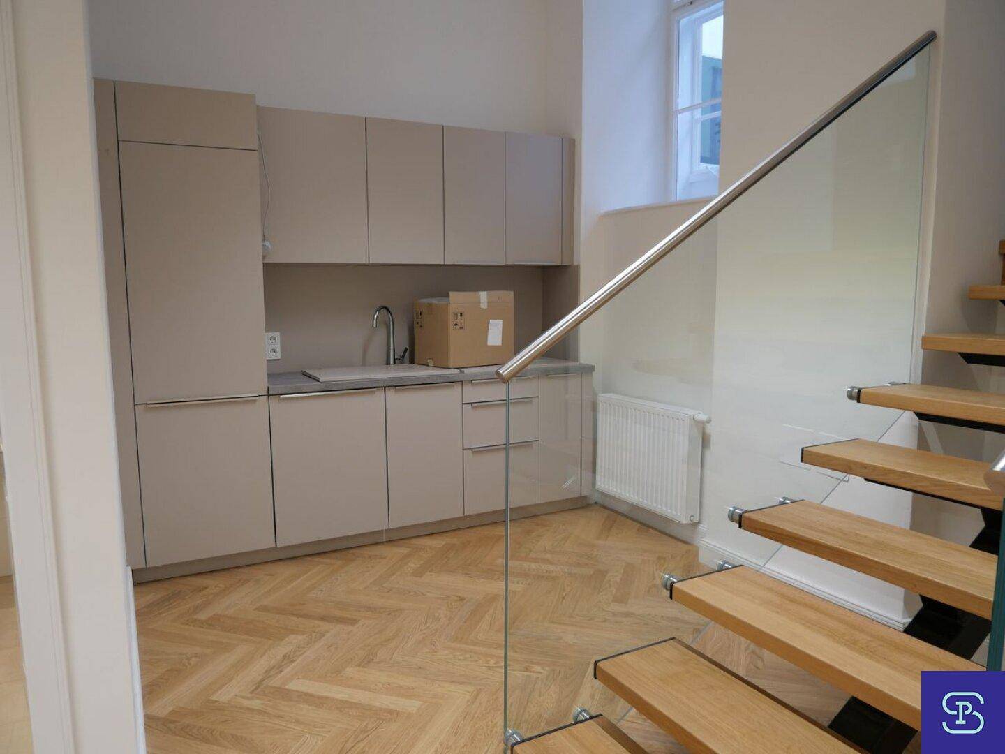 Moderne Küchenzeile mit beigefarbenen Schränken, Spüle und Fenster.