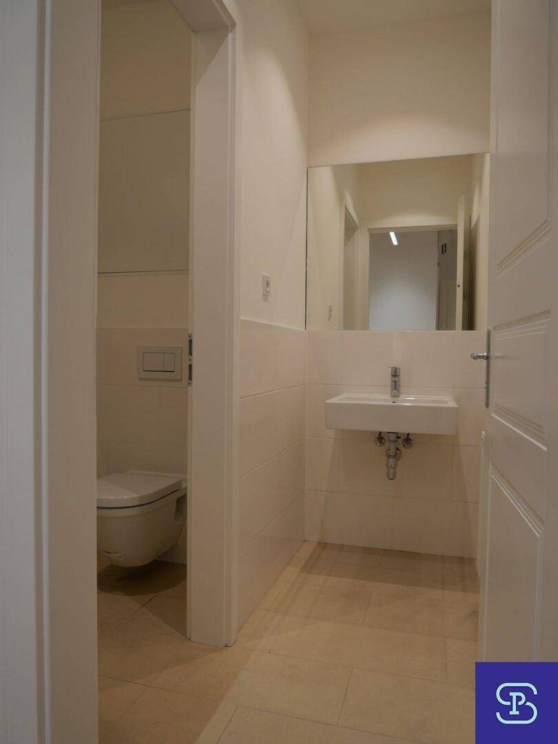 Modernes Gäste-WC mit wandhängender Toilette, Einzelwaschbecken und Spiegel.