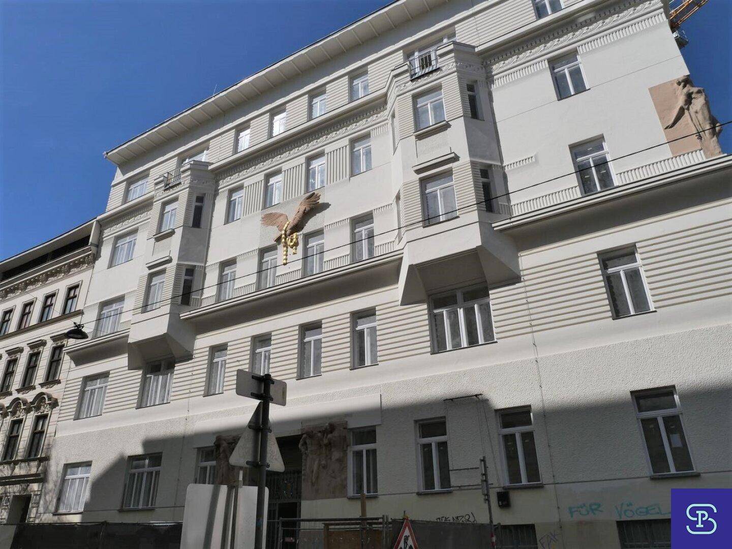 Fassade eines mehrstöckigen Gebäudes mit zahlreichen Fenstern und Balkonen.