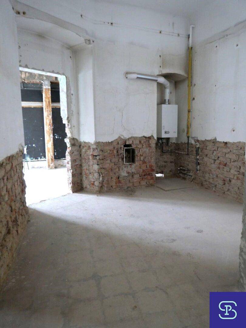 Hauswirtschaftsraum im Rohbau mit Gastherme an der Wand und freigelegten Ziegeln.