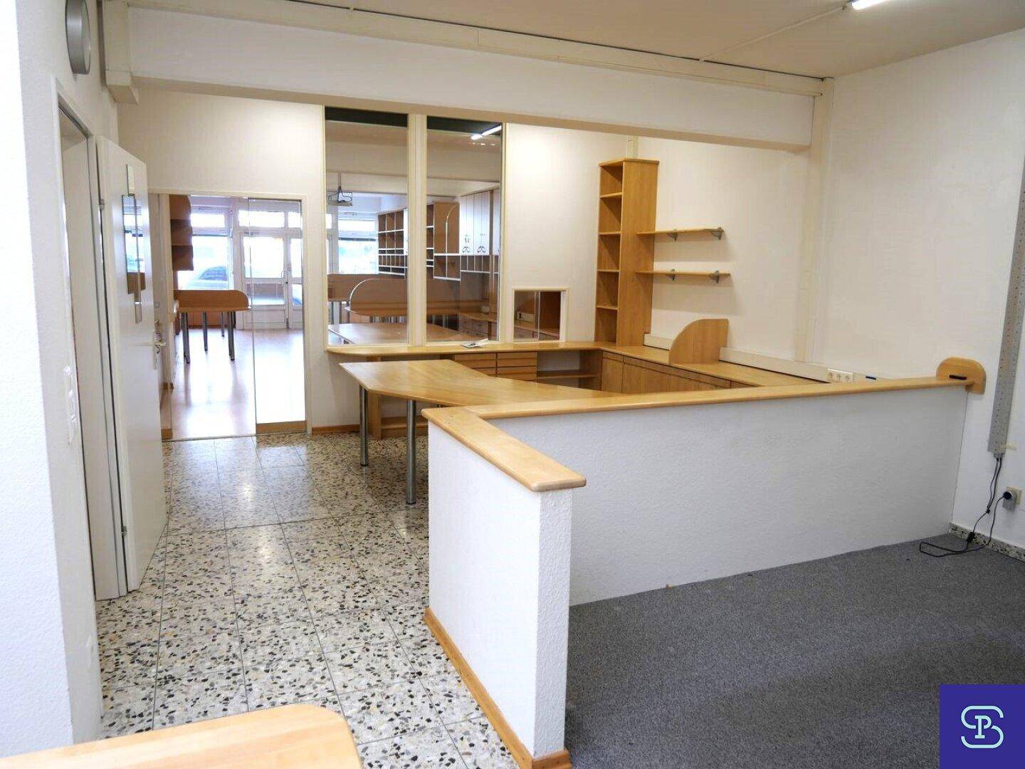 Eingangsbereich mit Empfangstheke, Teppichboden und Blick in weitere Büroräume.