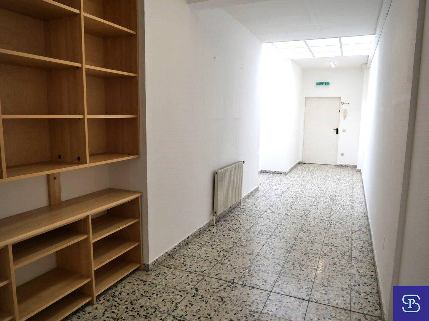 Heller Flur mit gefliestem Boden, Heizkörper und Regalen, führt zu weiteren Räumen.