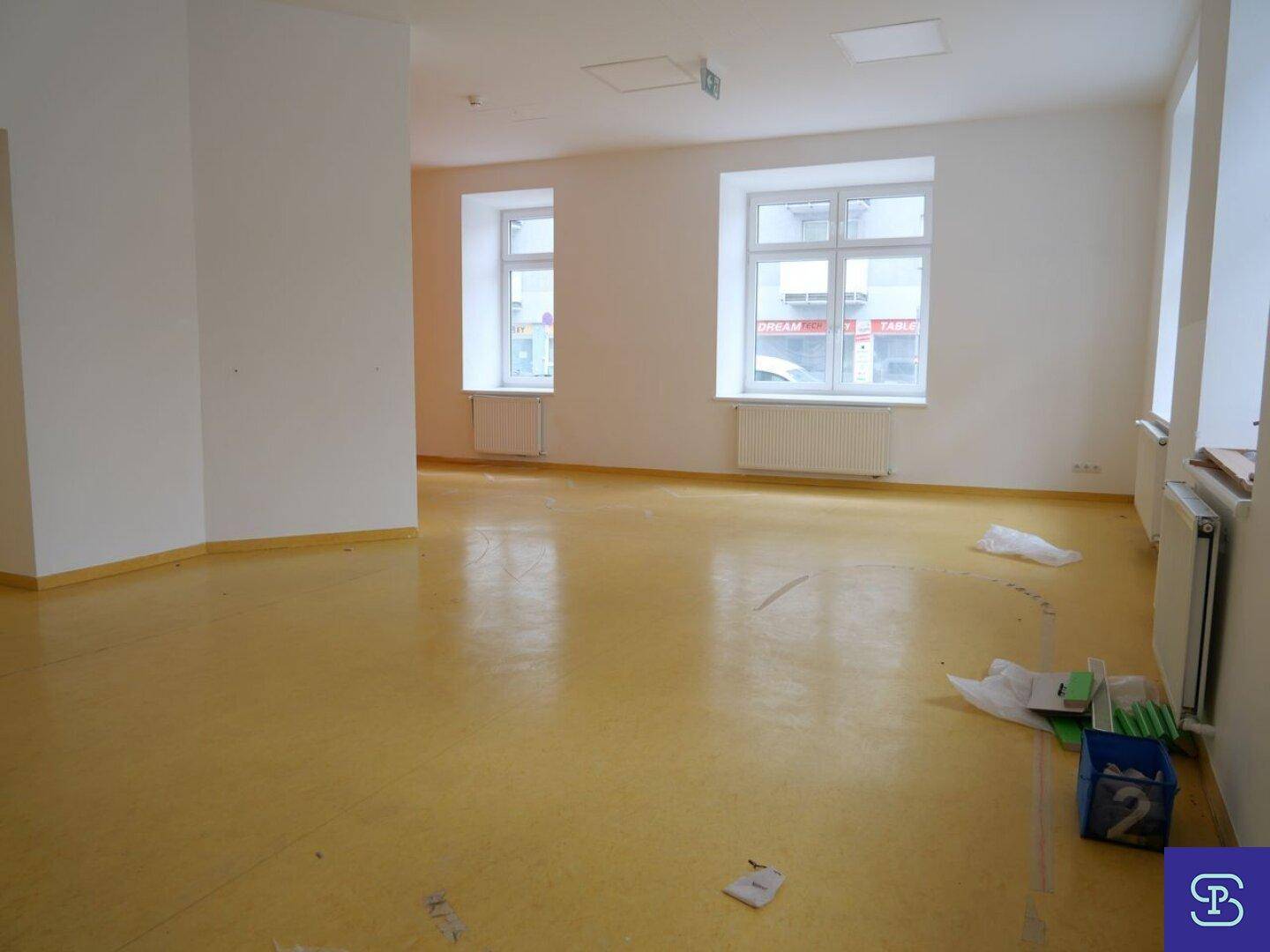 Heller Raum mit gelbem Linoleumboden und großen Fenstern, die viel Tageslicht bieten, in gutem Zustand.