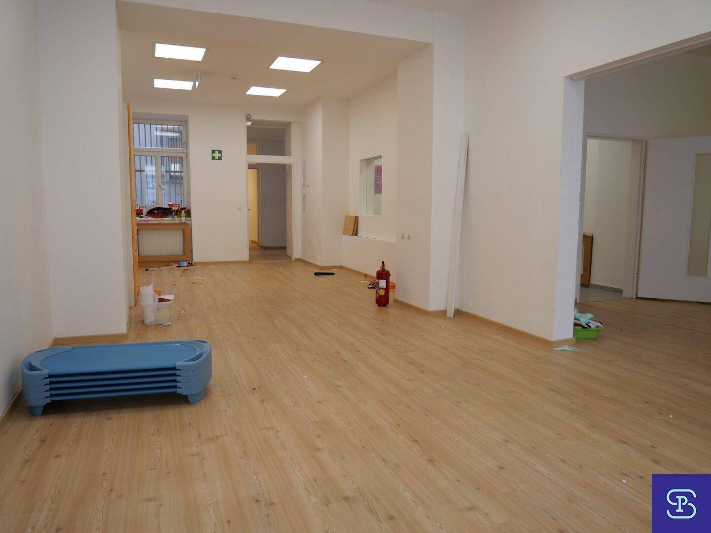 Heller, offener Raum mit Laminatboden, weißen Wänden und einem Feuerlöscher, in gutem Zustand.