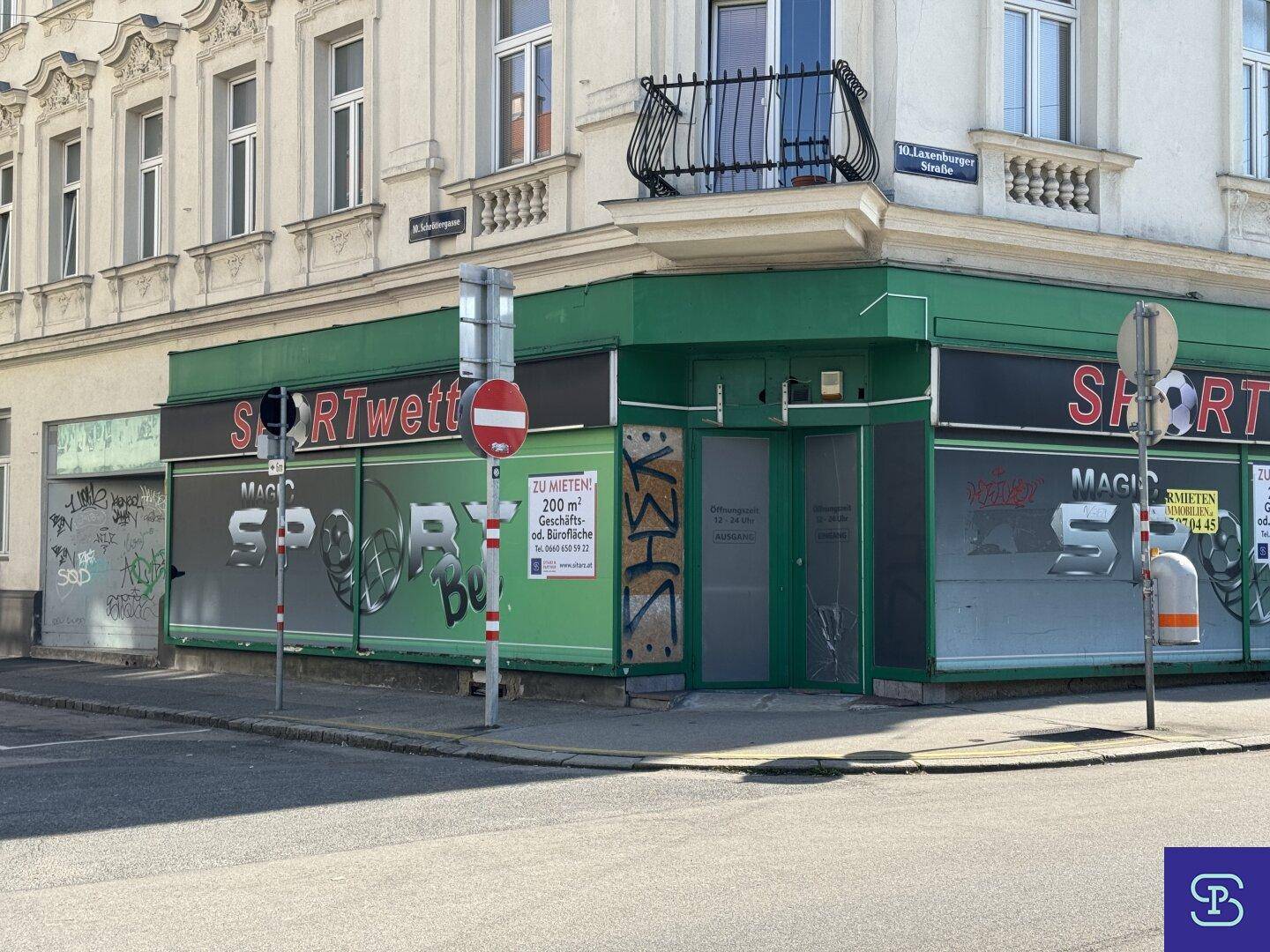 Außenansicht des Eckgebäudes mit kommerzieller Nutzung im Erdgeschoss und Wohnungen darüber.
