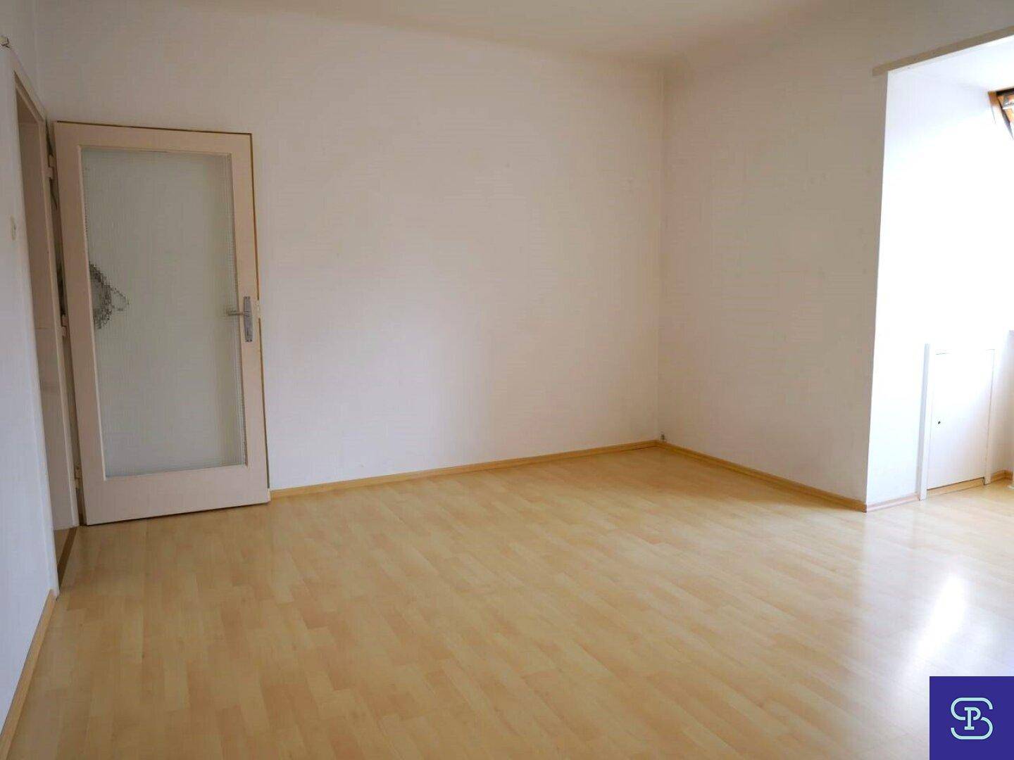 Heller Raum mit Laminatboden und einer Tür mit Milchglas, die viel Licht hereinlässt.