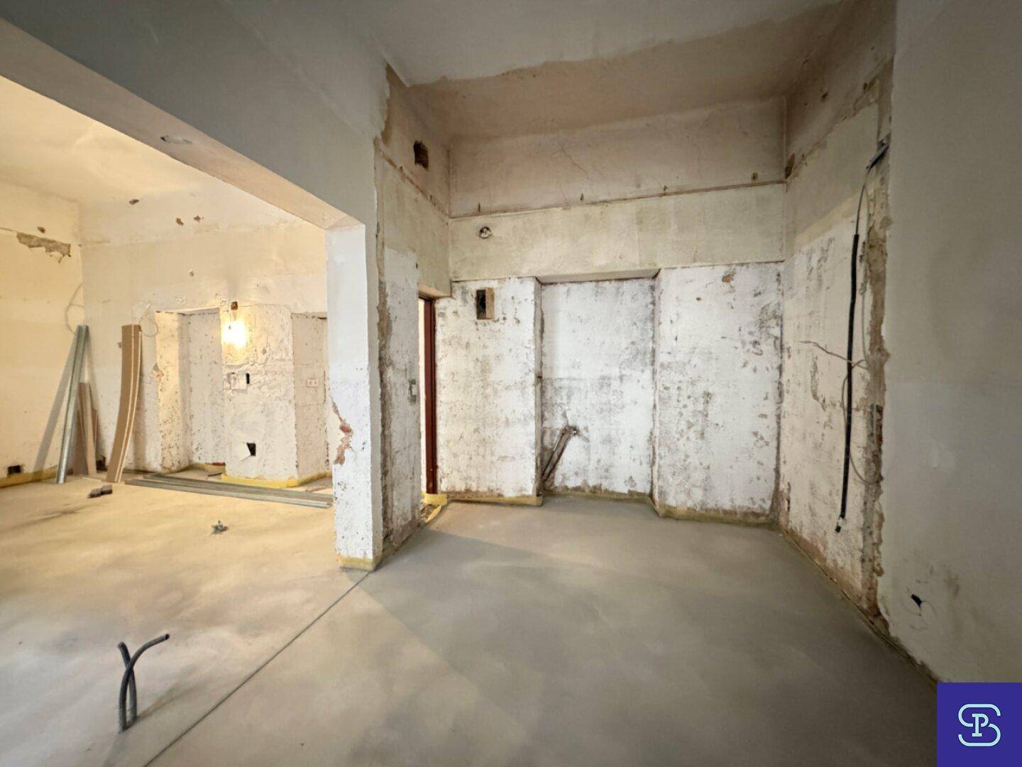 Raum in Renovierung mit freigelegten Wänden und Betonboden, bereit für den weiteren Ausbau.