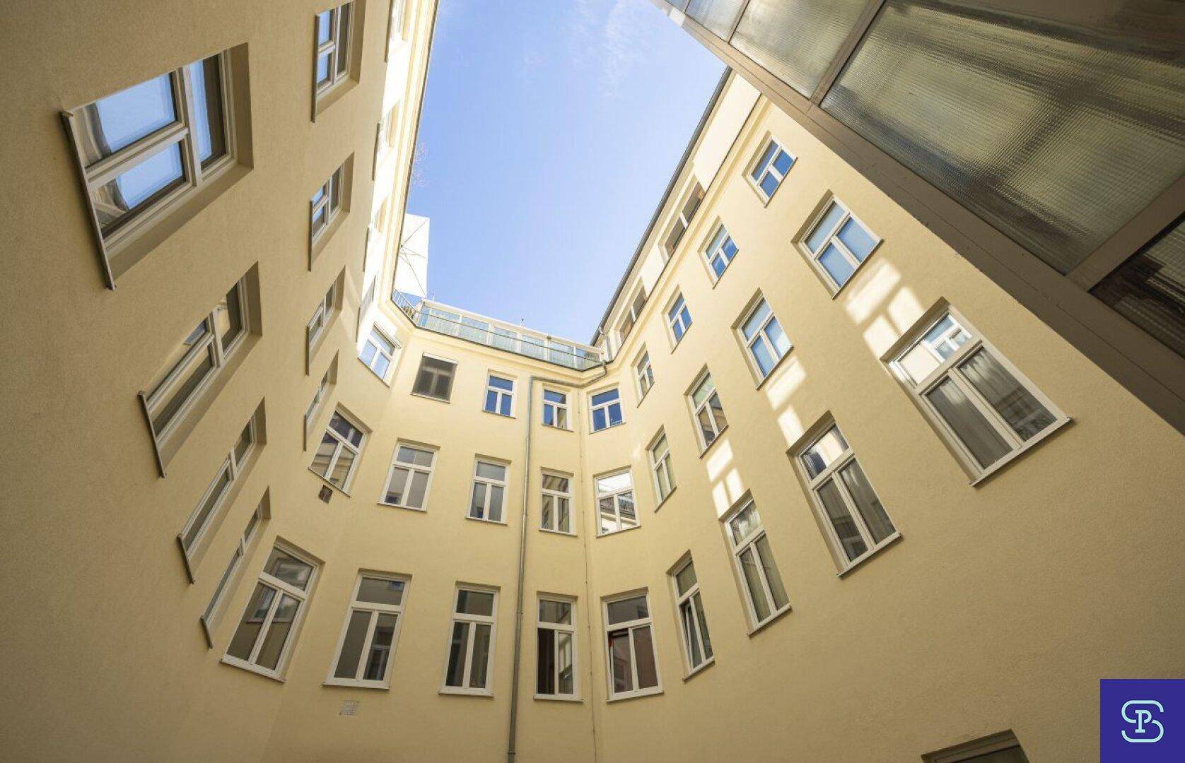 Innenhof eines Gebäudes mit vielen Fenstern und hellem Himmel, der viel Licht spendet.