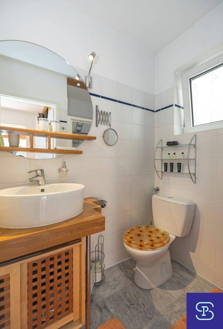 Helles Badezimmer mit Fenster, Waschtisch und WC, ausgestattet mit weißen Fliesen.