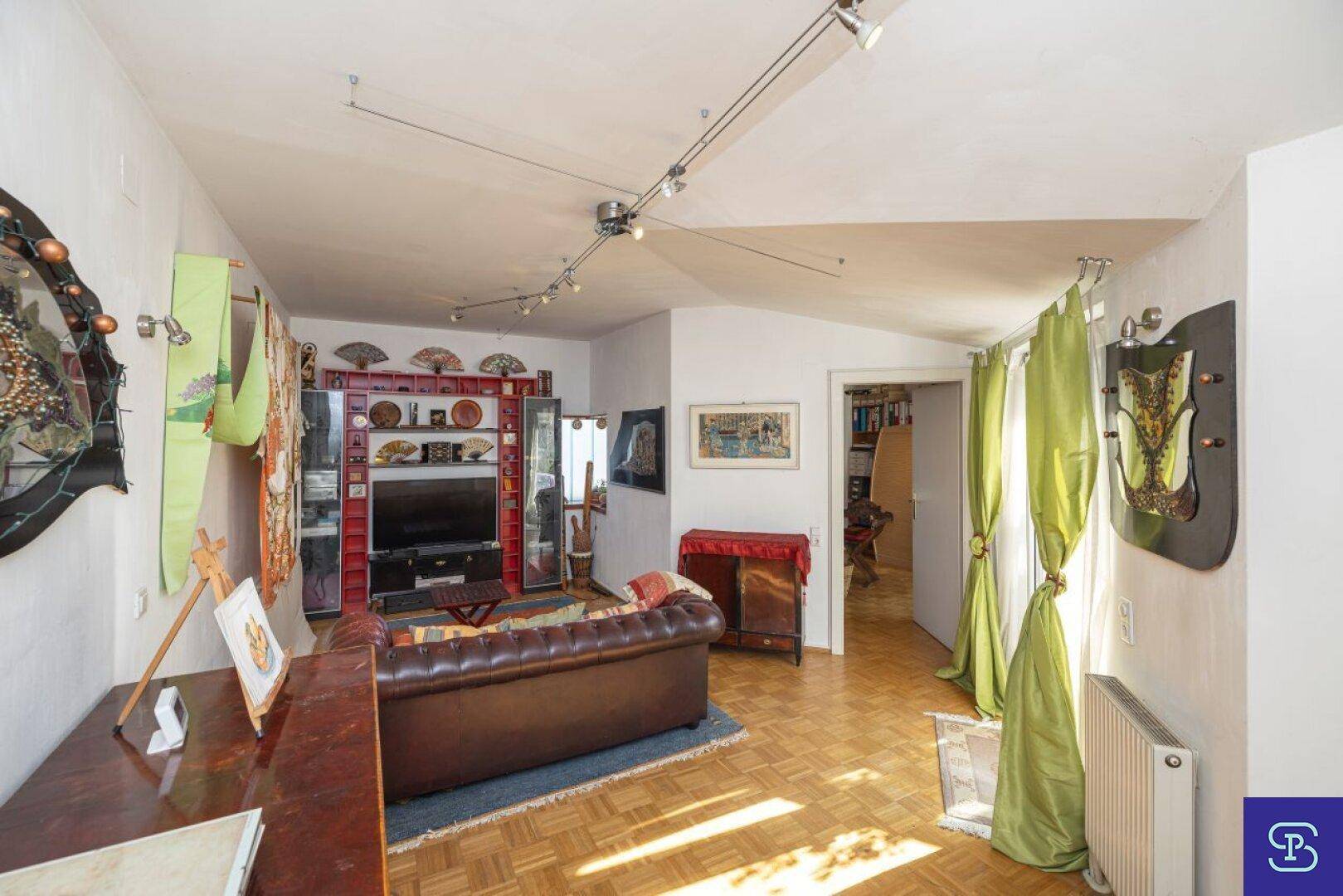 Gemütliches Wohnzimmer mit Parkettboden, Ledersofa und dekorativen Elementen.