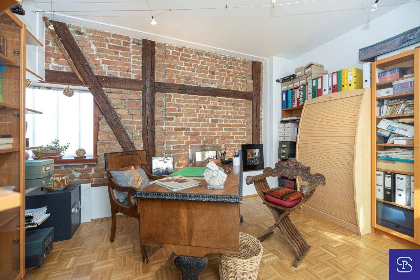 Historisches Arbeitszimmer mit Ziegelwand, Holzbalken und antiken Möbeln.