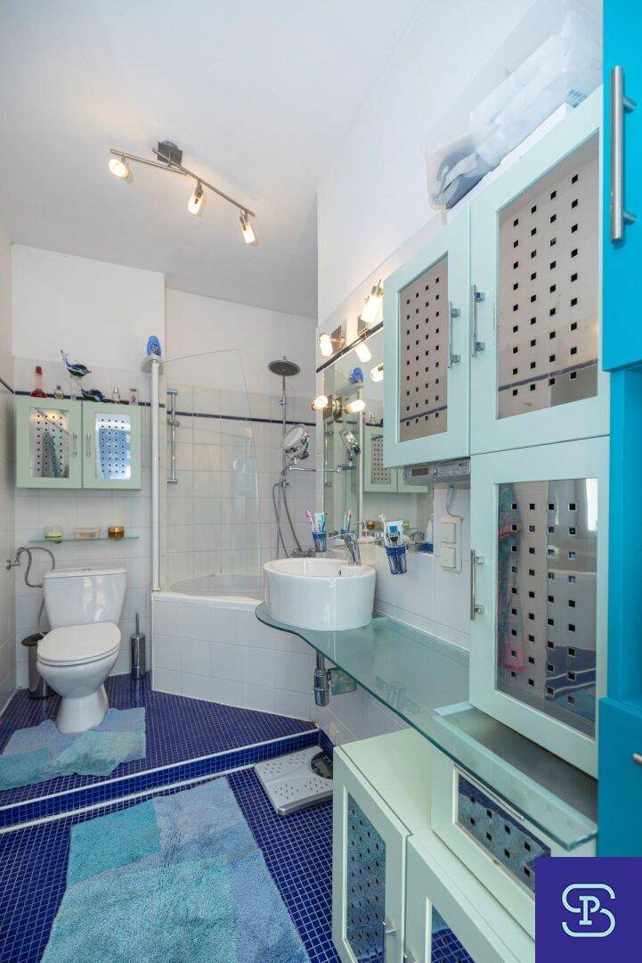Modernes Badezimmer mit blauen Fliesen, Badewanne mit Duschfunktion und Waschtisch.