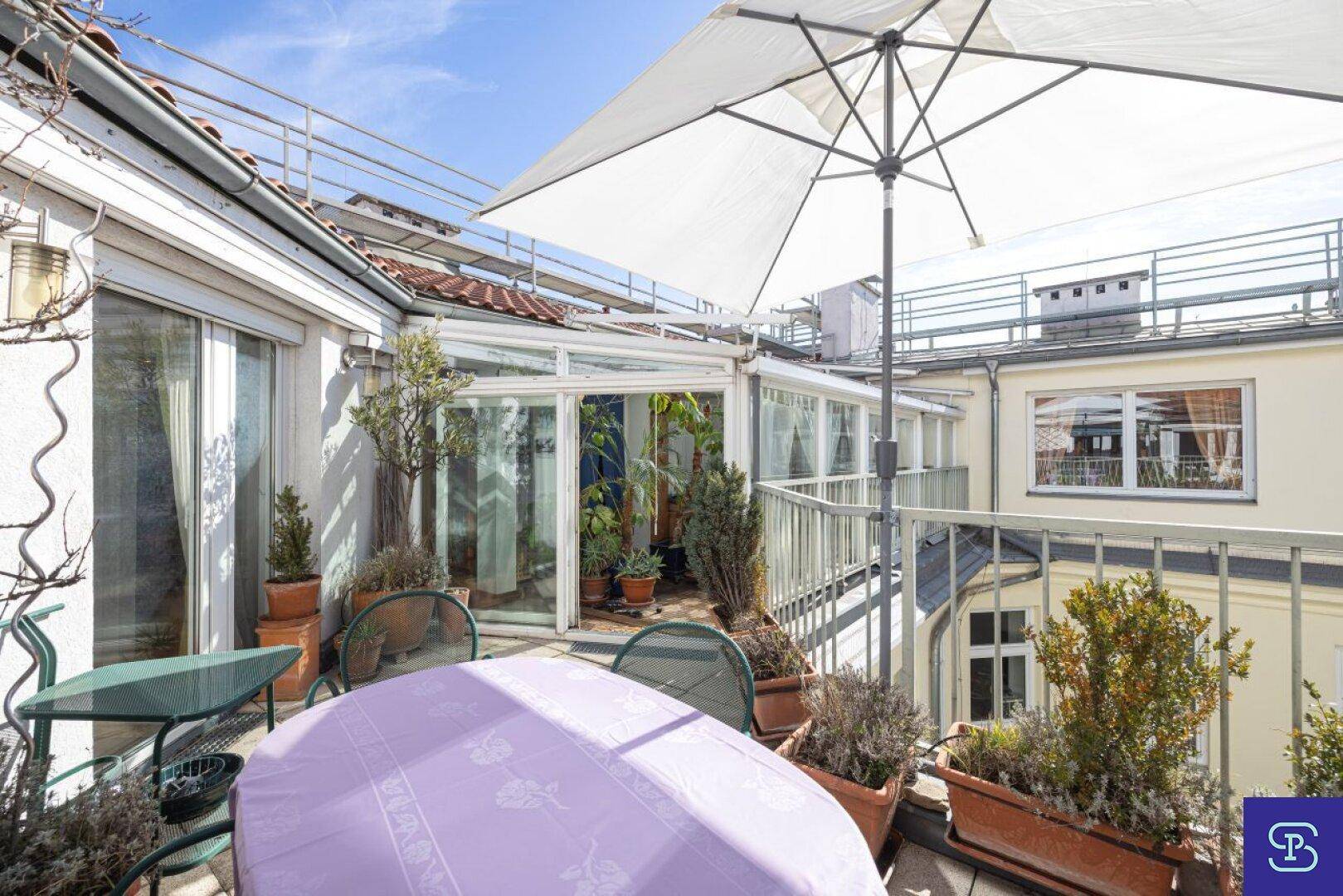 Sonnenterrasse auf dem Dach mit Gartenmöbeln, Sonnenschirm und Blick über die Dächer.