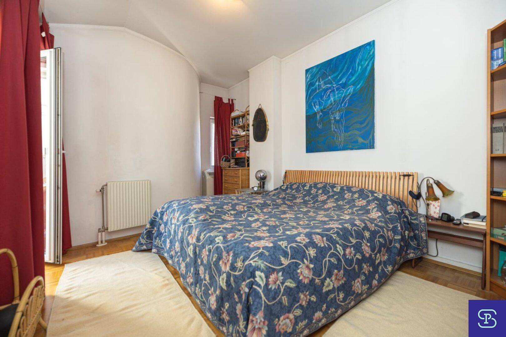 Schlafzimmer mit Doppelbett, Parkettboden und Zugang zu einem Balkon oder Terrasse.