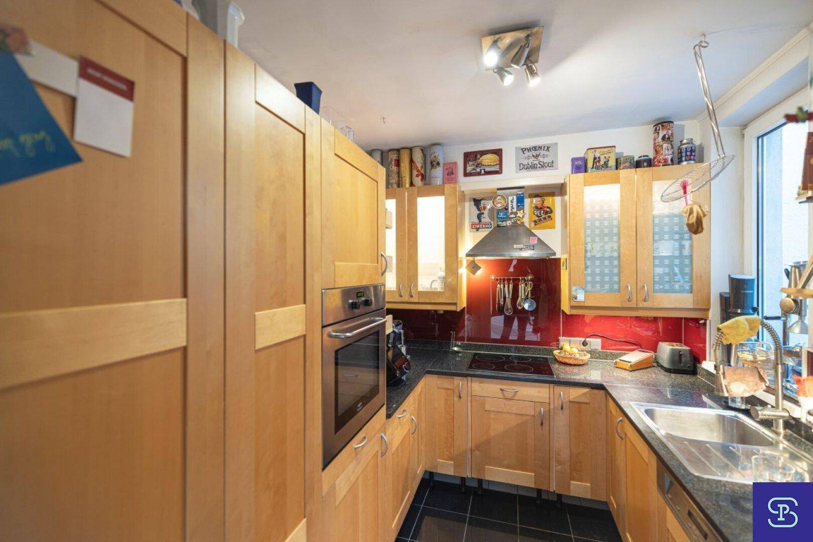Funktionale Küche mit Holzschränken, dunkler Arbeitsplatte und integrierten Geräten.