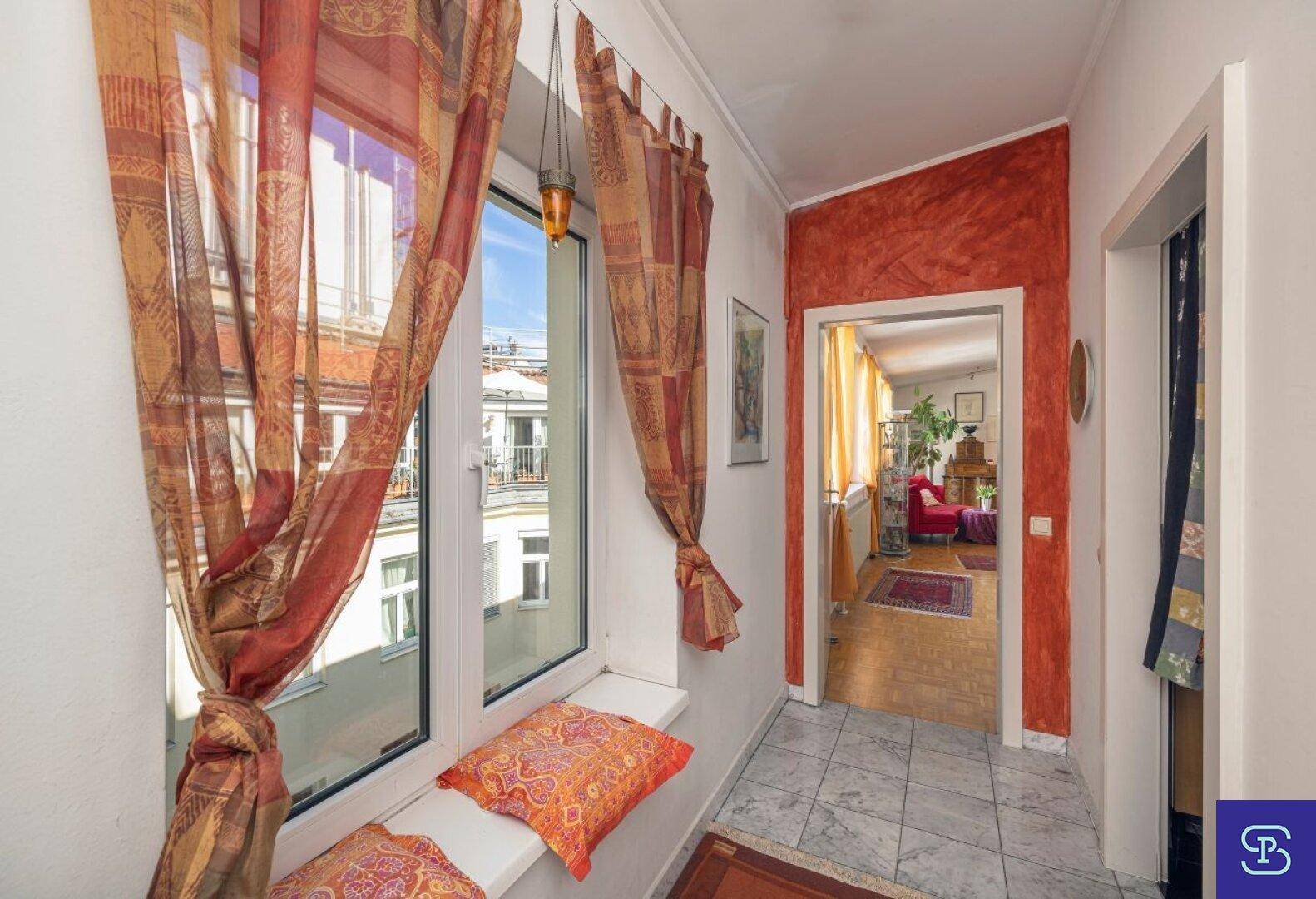 Heller Flur mit Fensterblick auf die umliegenden Gebäude und einer auffälligen roten Wand.