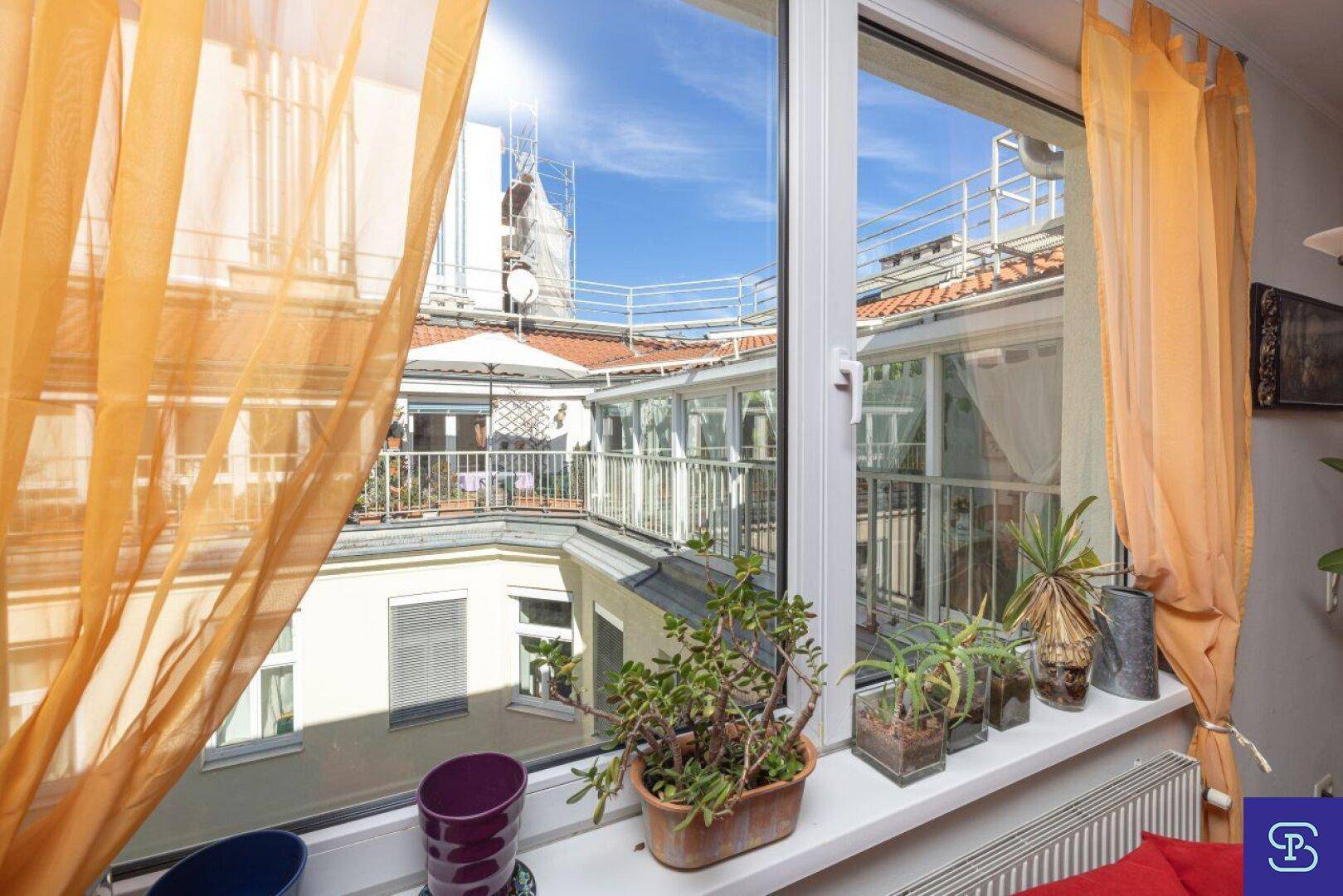 Blick aus dem Fenster auf die Dachterrasse und den Wintergarten, mit viel Tageslicht.