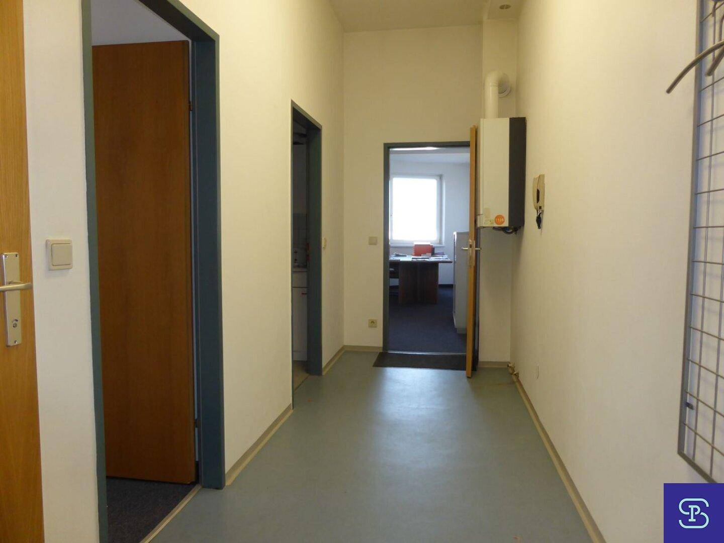 Heller Flur mit grauem Boden, weißen Wänden und Zugang zu mehreren Räumen, inklusive Heizungsanlage.