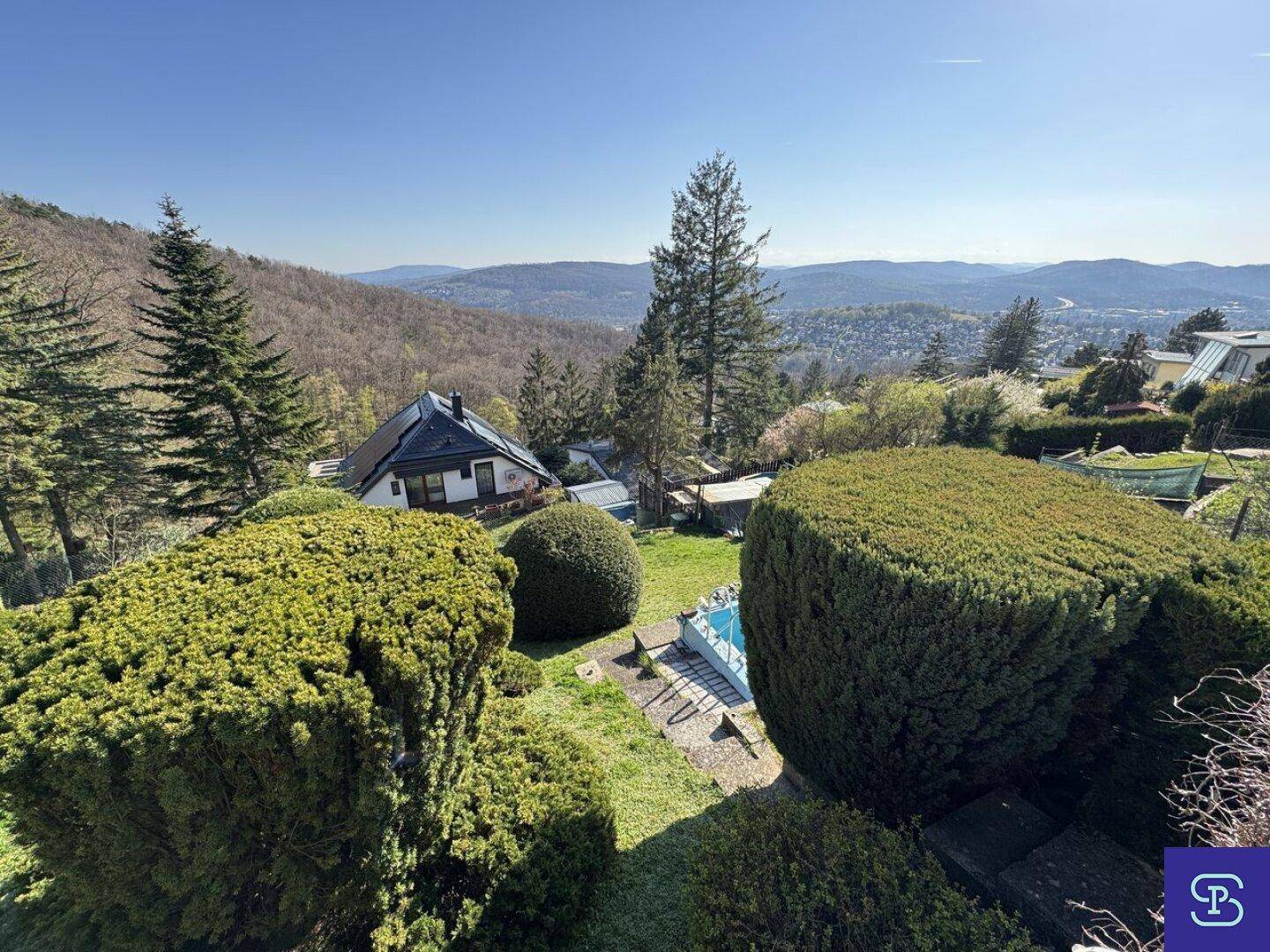 Garten mit gepflegten Sträuchern und einem kleinen Pool, der einen weiten Ausblick bietet.