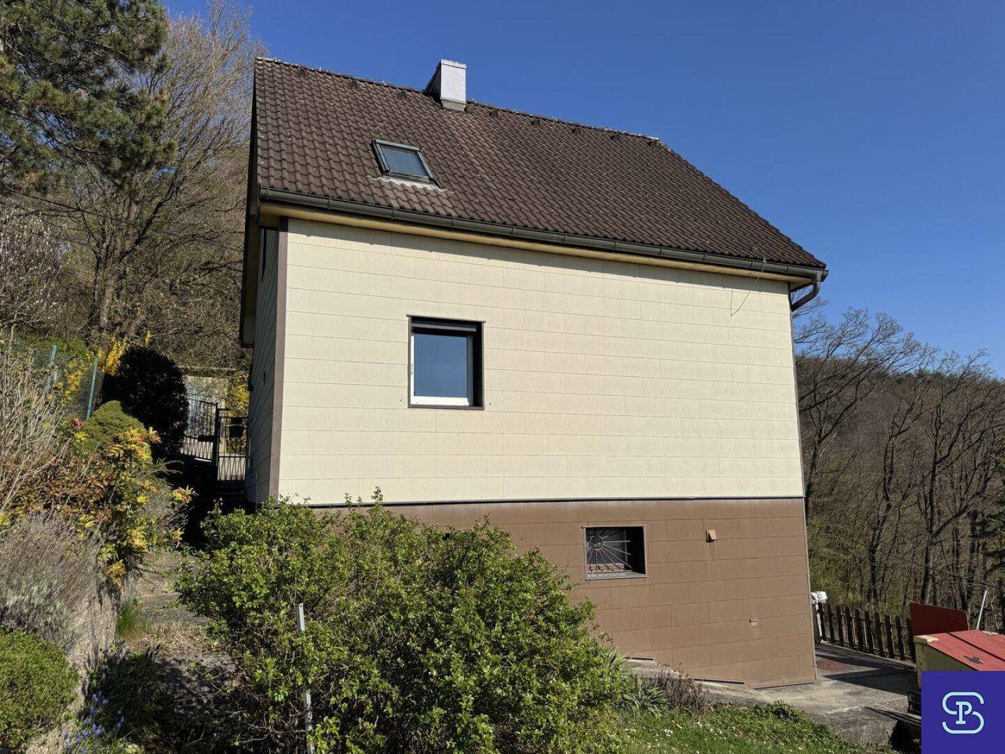 Seitenansicht des Hauses mit Satteldach und einem kleinen Fenster im Untergeschoss.