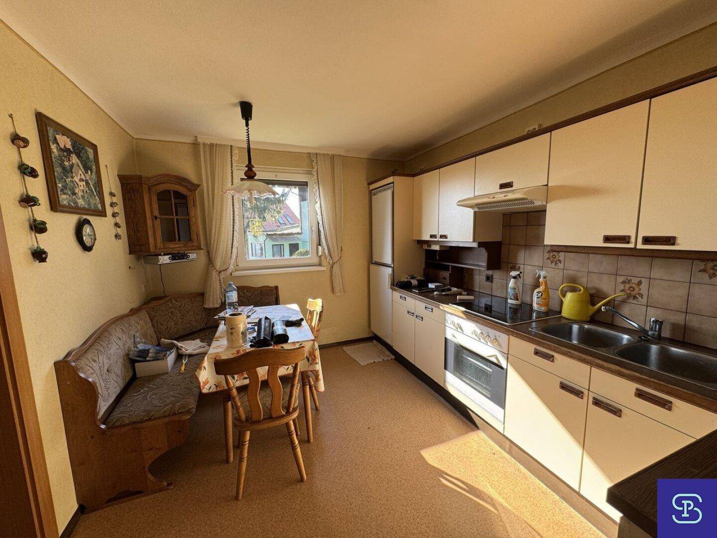 Traditionelle Einbauküche mit Essbereich, hellen Schränken und Fensterblick ins Grüne.