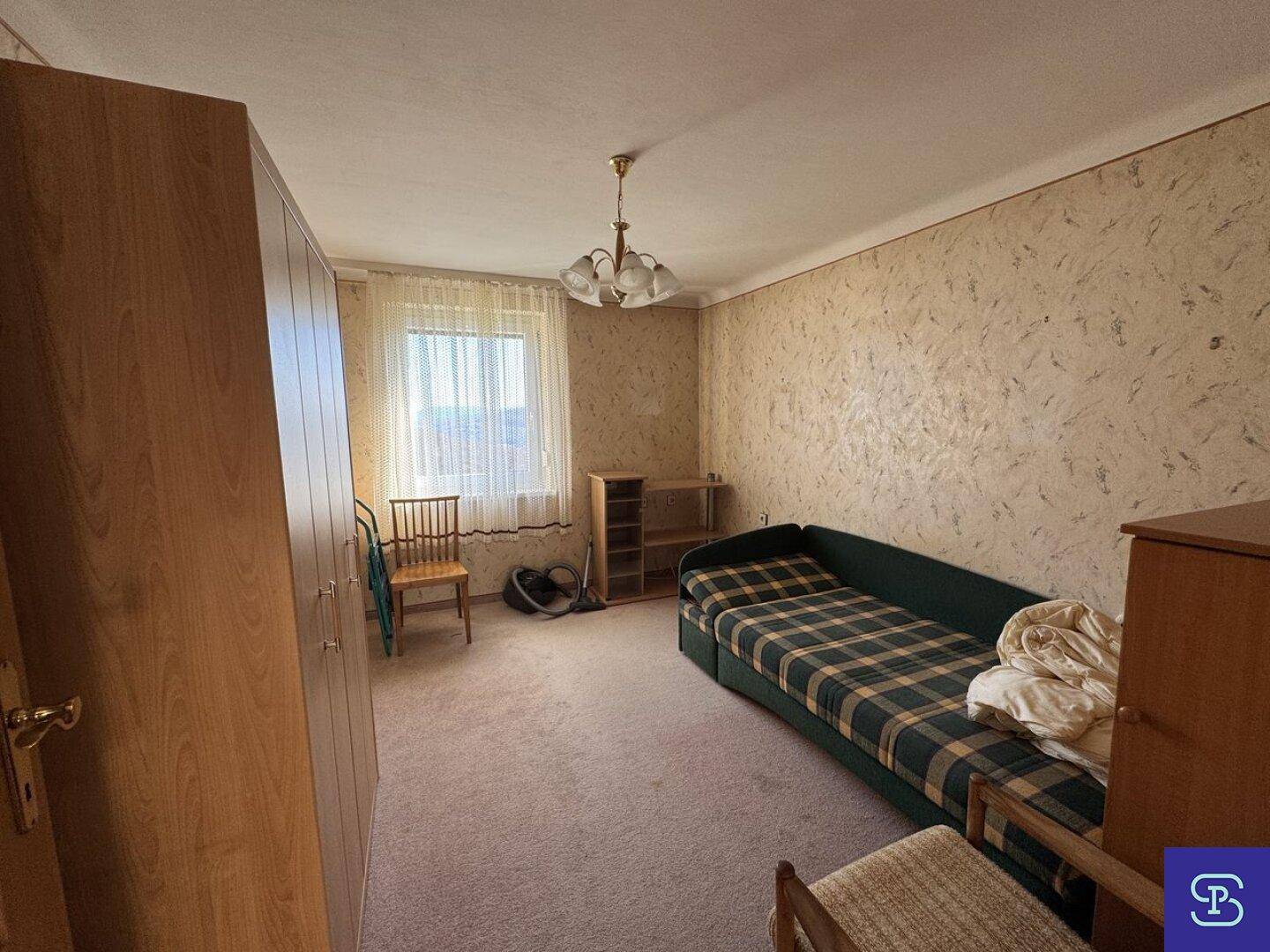 Schlafzimmer mit Teppichboden, Einzelbett und einem Fenster, das viel Tageslicht hereinlässt.