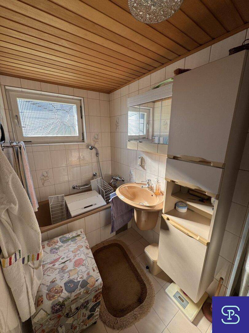 Helles Badezimmer mit Duschbereich, Waschbecken und Fenster für gute Belüftung.