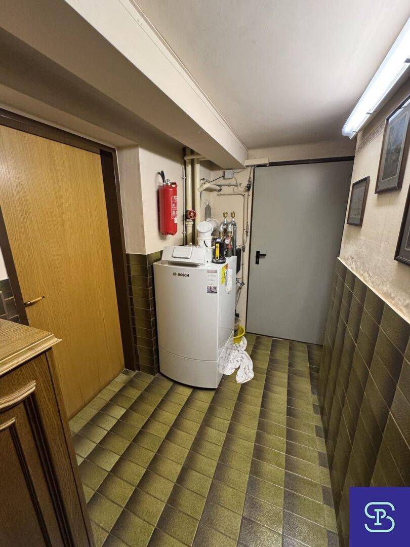 Heizungsraum im Keller mit einem modernen Heizkessel und Fliesenboden.
