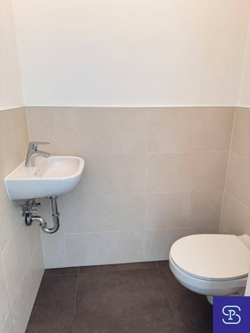 Separates Gäste-WC mit modernem Waschbecken und wandhängender Toilette.