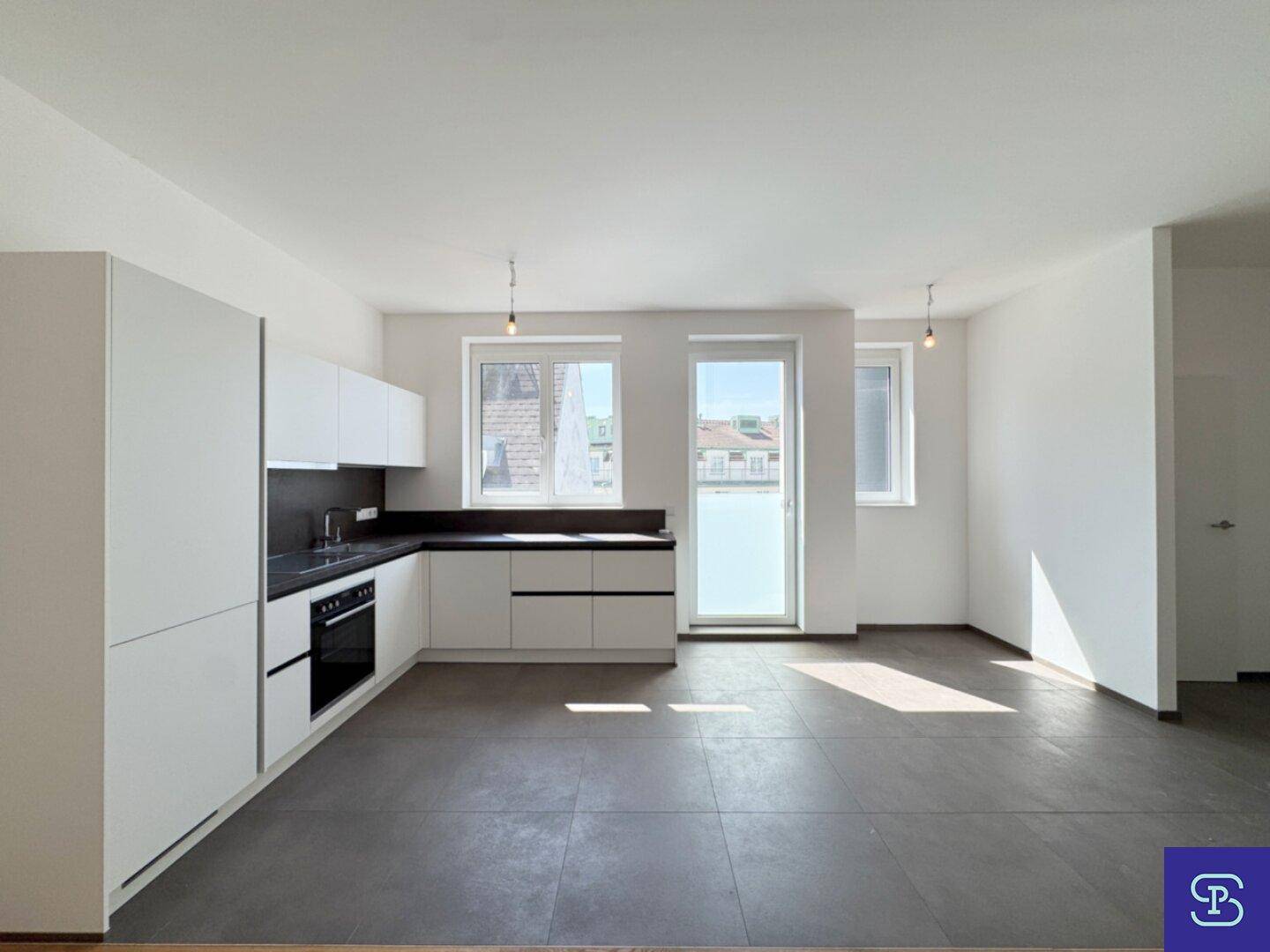 Moderne Einbauküche mit weißen Fronten, dunkler Arbeitsplatte und viel Tageslicht.
