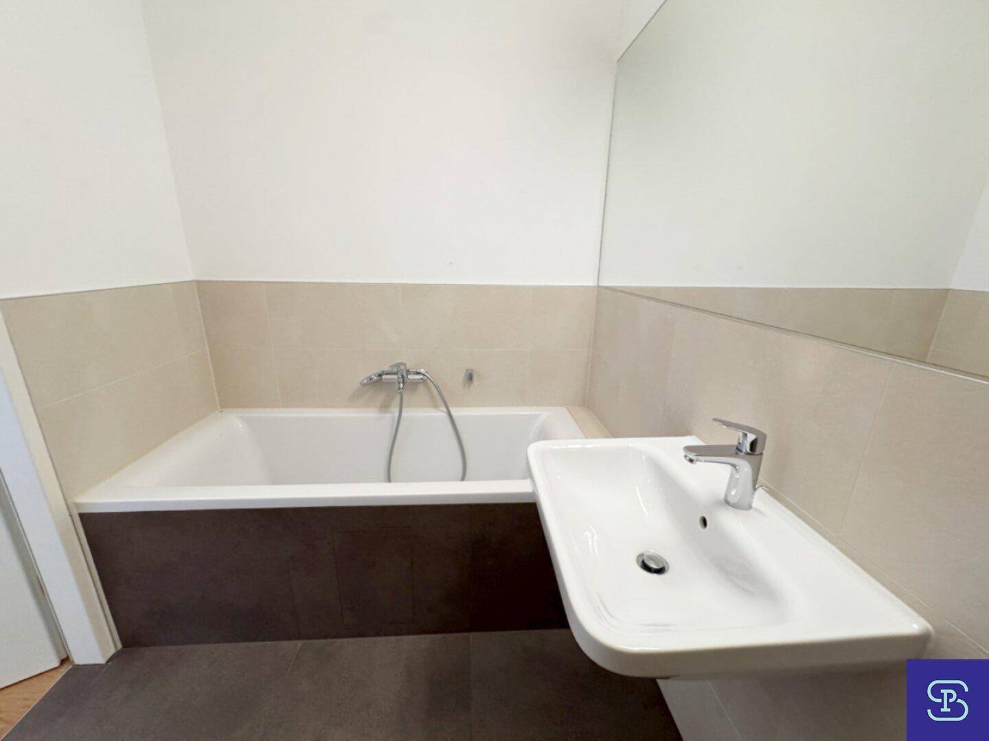 Helles Badezimmer mit Badewanne, modernem Waschbecken und großem Wandspiegel.