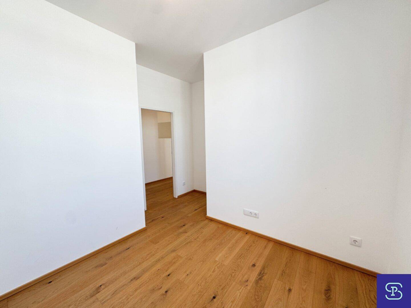 Helles Zimmer mit Parkettboden und weiß gestrichenen Wänden, ideal als Schlaf- oder Arbeitszimmer.