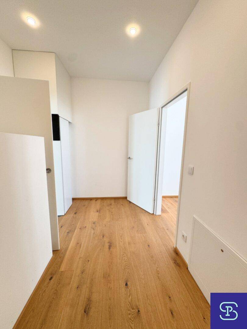 Moderner Flur mit Parkettboden und weiß gestrichenen Wänden, der die Räume verbindet.