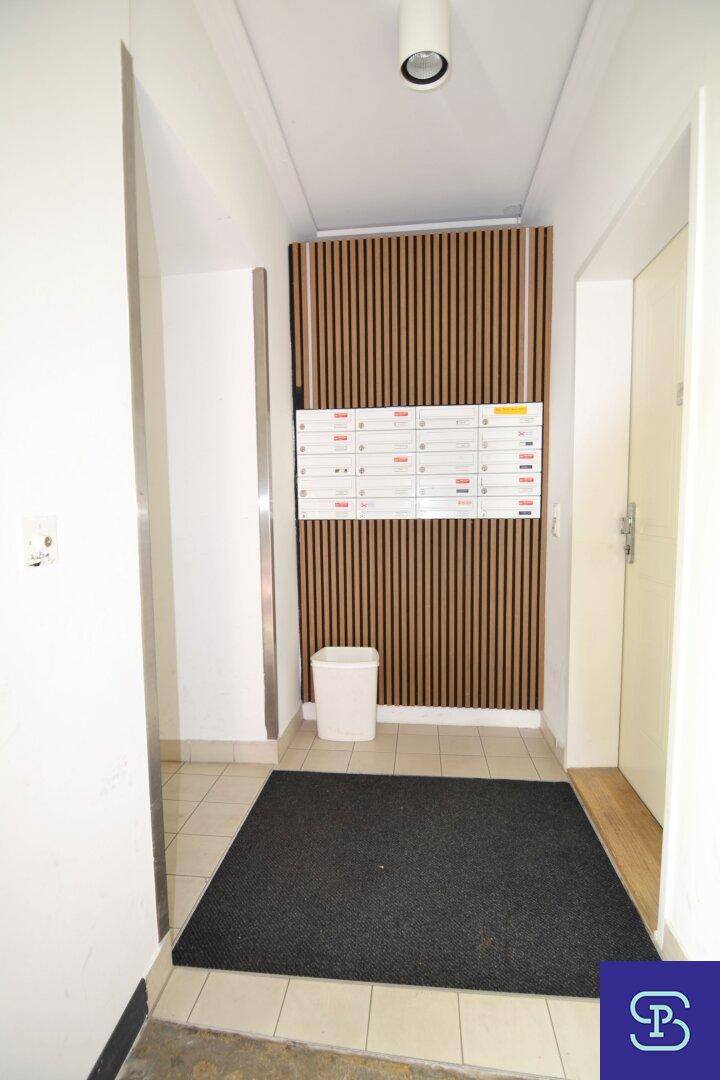 Eingangsbereich mit Briefkästen, Fliesenboden und dekorativer Holzlamellenwand.