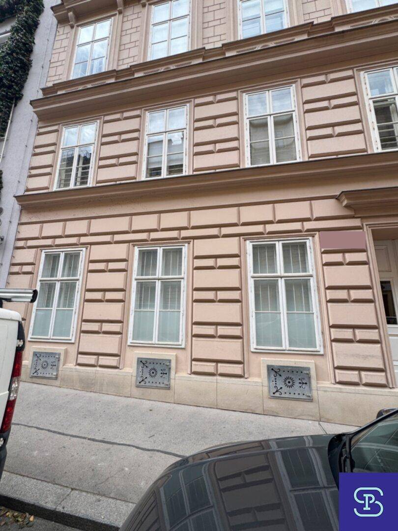 Klassische Fassade eines Altbaus mit mehreren Fenstern und dekorativen Elementen.