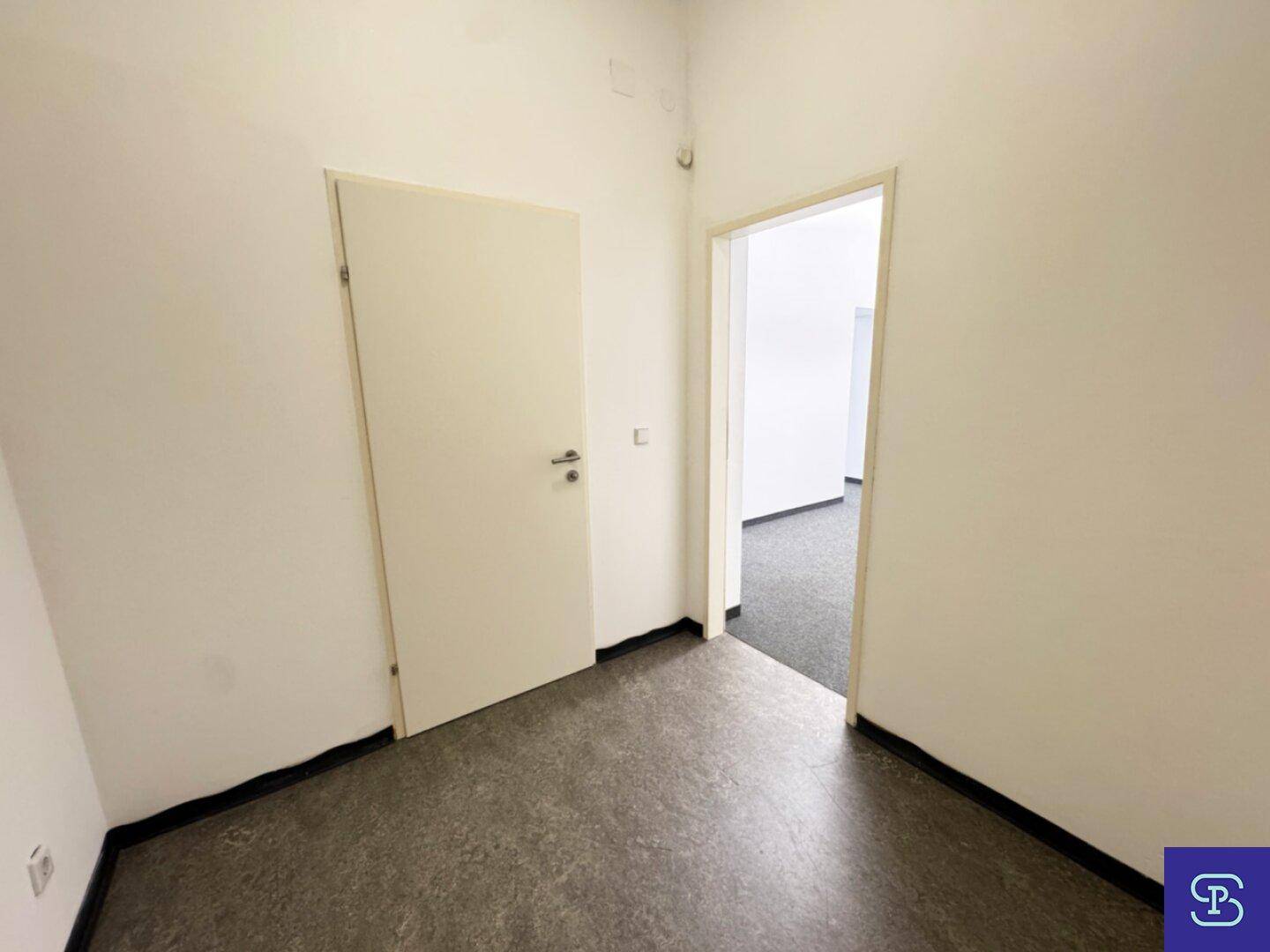 Heller Flur mit hellem Boden und einer Tür, die zu weiteren Räumen führt.