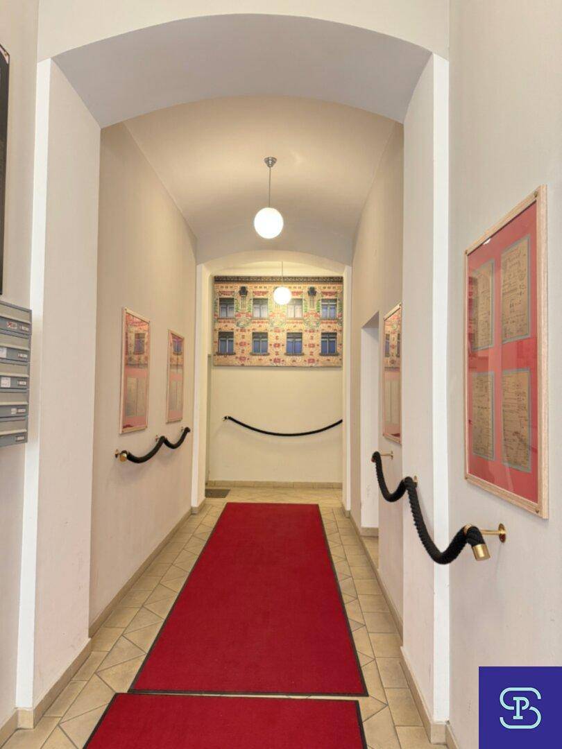 Historischer Eingangsbereich mit rotem Teppich, gewölbter Decke und dekorativen Handläufen.